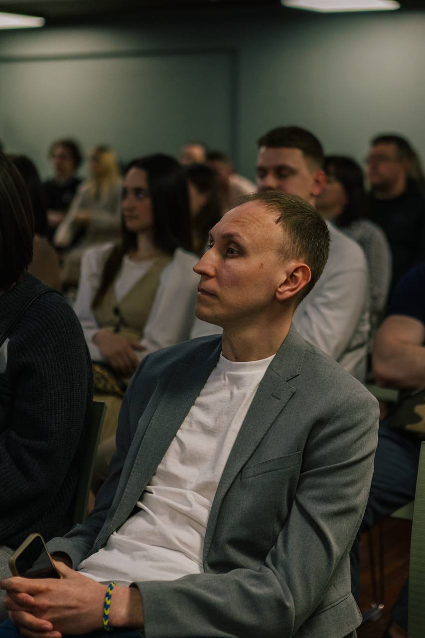 Учасник уважно слухає виступ, сидячи в залі